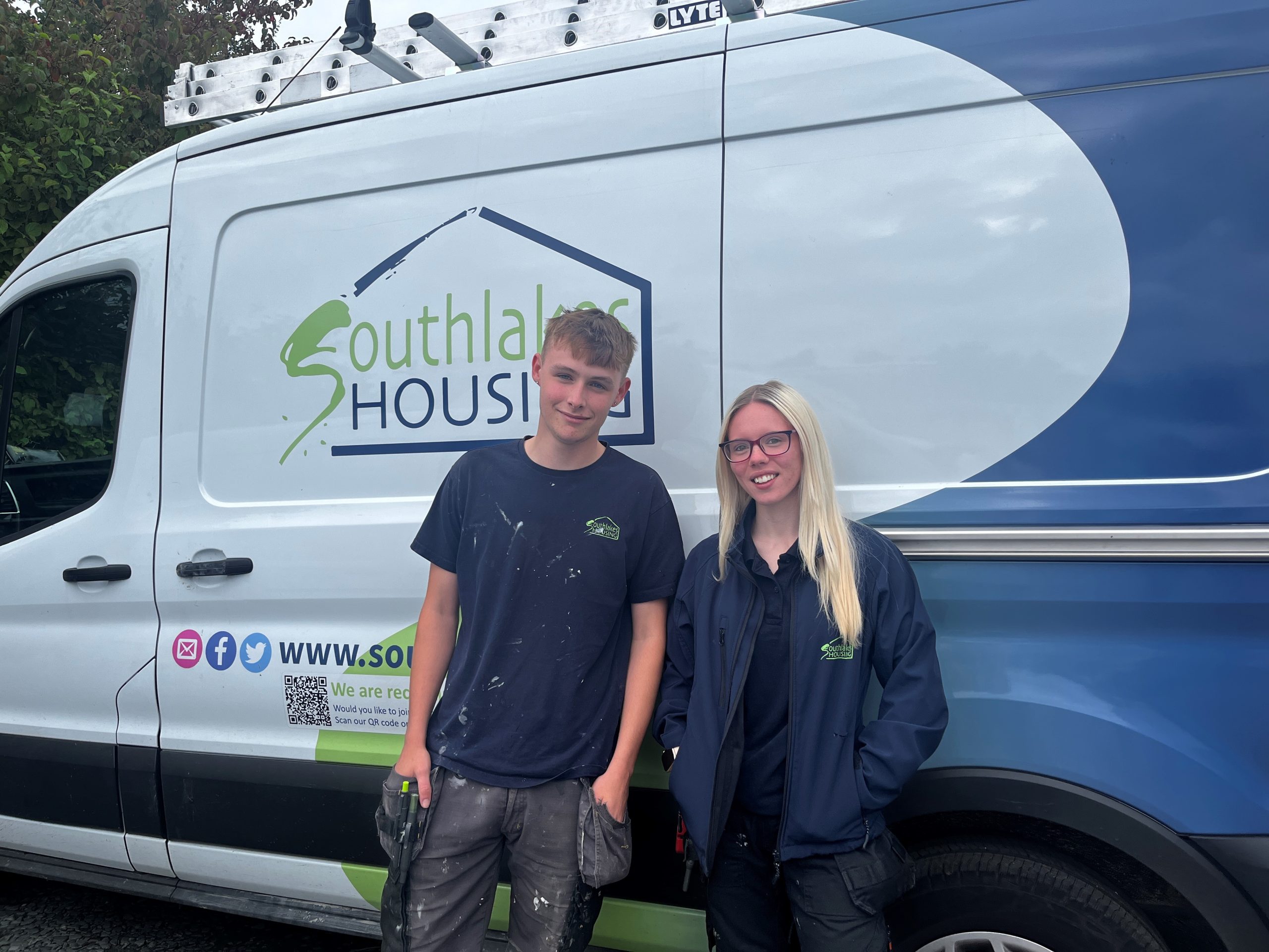 A male & female trade apprentice in front of an South Lakes Housing van